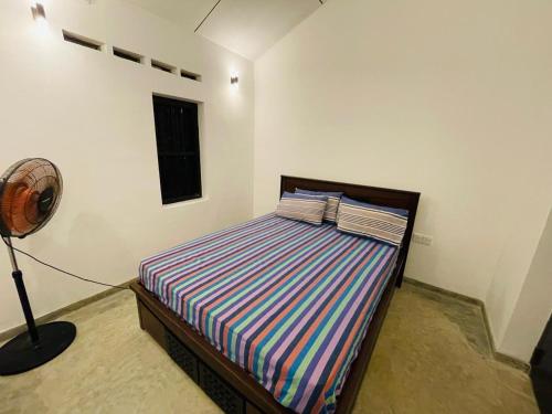 Un dormitorio con una cama y un ventilador. en Berg House Mirissa, en Mirissa