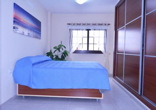 a bedroom with a blue bed and a window at Casa Yoel in Granadilla de Abona