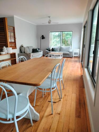 a dining room and living room with a wooden table and chairs at Private Bush & Beach Retreat in Eudlo