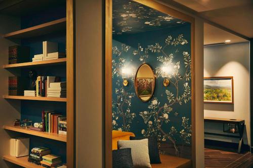 a room with a blue wall with a mirror at The Draftsman, Autograph Collection in Charlottesville