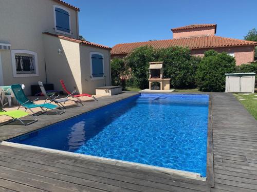 une piscine avec des chaises et une maison dans l'établissement Villa climatisée avec piscine privée, 3 ch, jardin, parking et WIFI à Elne - FR-1-776-113, à Elne