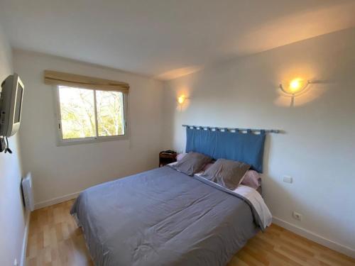 - une chambre avec un lit doté d'une tête de lit bleue et d'une fenêtre dans l'établissement T2 cabine calme prox. Boudigau, terrasse, parking, 4 pers. - FR-1-413-252, à Capbreton