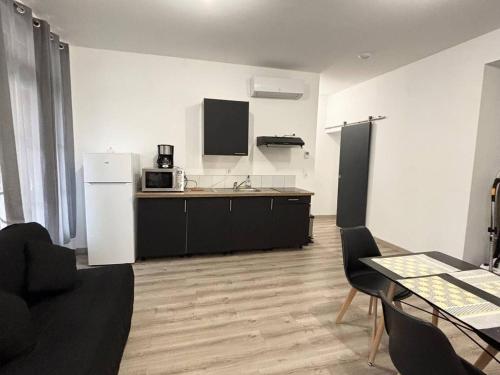 une cuisine avec une table et un réfrigérateur blanc dans l'établissement F2 meublé avec balcon, clim, WIFI, animaux admis - 50m des thermes - FR-1-703-198, à Amélie-les-Bains-Palalda