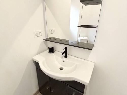 une salle de bain avec un lavabo blanc et un miroir dans l'établissement F2 meublé avec balcon, clim, WIFI, animaux admis - 50m des thermes - FR-1-703-198, à Amélie-les-Bains-Palalda