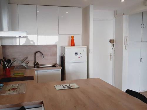 une cuisine avec une table en bois et un réfrigérateur blanc dans l'établissement Appartement rénové 3 pièces avec parking et clim, proche plage - FR-1-782-72, au Barcarès