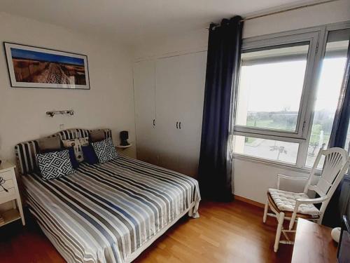 une chambre avec un lit, une chaise et une fenêtre dans l'établissement Appartement rénové 3 pièces avec parking et clim, proche plage - FR-1-782-72, au Barcarès