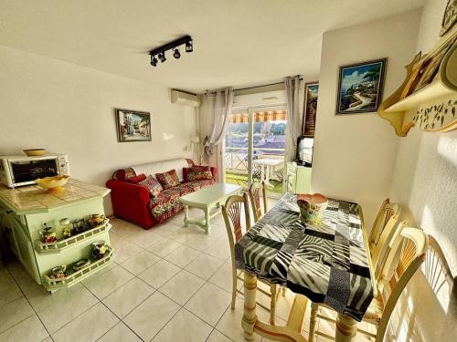 un salon avec une table et un canapé rouge dans l'établissement T2 Climatisé Proche Plage avec Terrasse et Garage - FR-1-816-14, au Lavandou