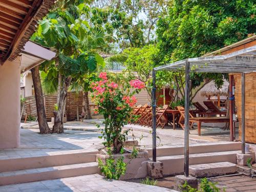 a garden with a greenhouse and a table with pink flowers at Jati Village, Party Hostel and Bungalows in Gili Trawangan