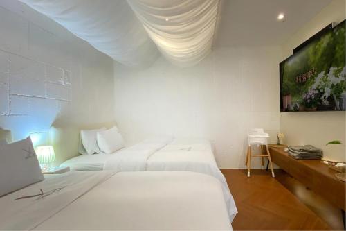 a white bedroom with two beds and a tv at Hotel Voll in Seoul