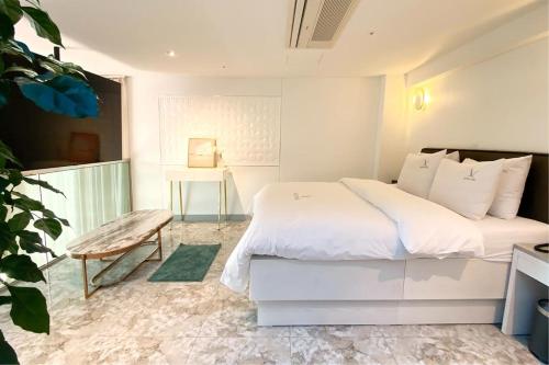 a white bedroom with a bed and a table at Hotel Voll in Seoul