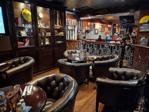 - un bar avec des fauteuils en cuir et une table dans l'établissement Le Vésuve - arrivée autonome, à Vierzon