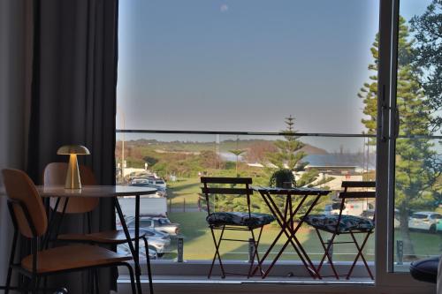 a room with a table and chairs and a large window at Dee Why Beach - Surfrider Studio 22 in Deewhy