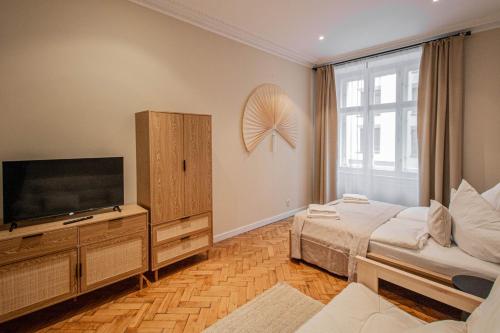 a bedroom with a television and a bed and a couch at Radost Residence The Heart of Unique Living in Prague