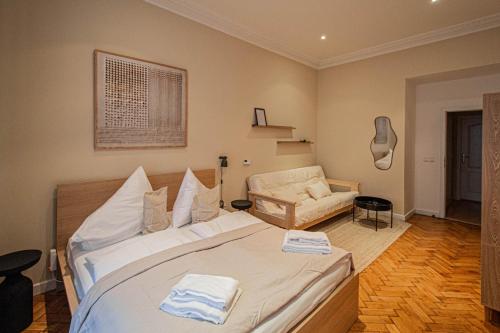 a bedroom with a large white bed and a chair at Radost Residence The Heart of Unique Living in Prague