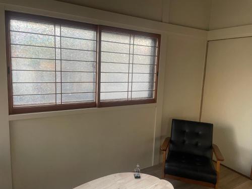 a room with two windows and a table and a chair at Hakuna Matata in Minamiawaji