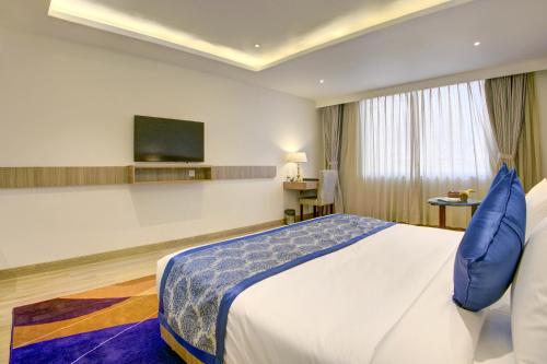 a hotel room with a bed and a flat screen tv at Cygnett Inn Airport in Mohāna