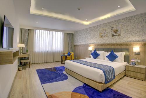 a hotel room with a large bed with blue pillows at Cygnett Inn Airport in Mohāna
