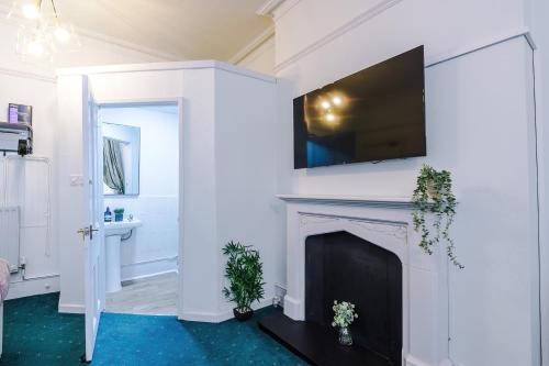 a living room with a fireplace with a flat screen tv above it at Victoria Park Studio 6 - Mins Walk To Train Station, Free Parking, Free Netflix, Prime & Disney in Leamington Spa