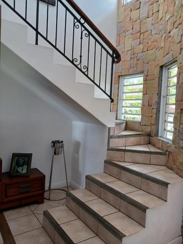 a staircase in a home with a stone wall at Chambre d'hôte La Mare Ronde in Grand Baie