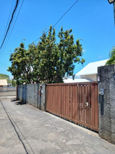 a fence with a wooden gate on a street at Chambre d'hôte La Mare Ronde in Grand Baie