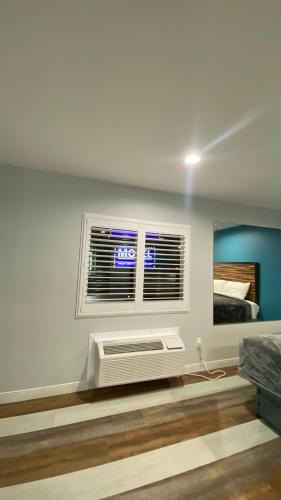a bedroom with a bed and a window with a air conditioner at Plaza Inn Motel - Los Angeles area in Rosemead