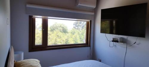 a bedroom with a large window and a television at Hermosa casa en condominio in El Quisco
