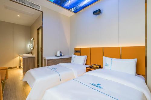 two beds with white sheets in a hotel room at Dequan Luxury Hotel CBD BranchCoffee, fruits, snacks, a gym and a laundry room are provided for free in the lobby in Beijing
