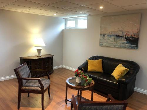 a living room with a black leather couch and a table at Super Cosy Peaceful room with Garden view free Parking in Toronto