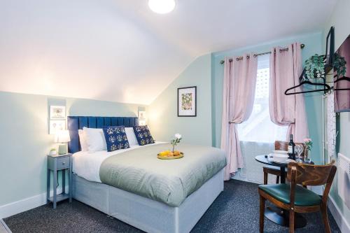 a blue and white bedroom with a bed and a table at Victoria Park Studio 8 with Private Off-suite Shower Room down a flight of stairs from the main room, Free Parking, Free Netflix, Prime & DisneyPlus in Leamington Spa