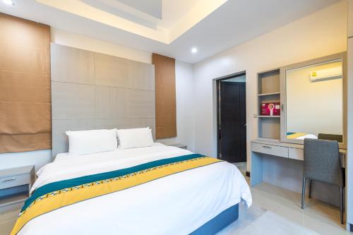 a bedroom with a bed and a desk and a mirror at Kana Hotel Phuket普吉岛卡娜酒店 in Rawai Beach