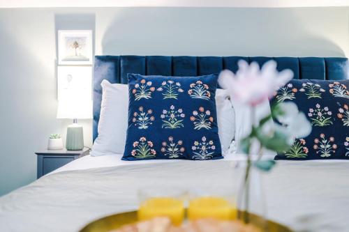 a bed with blue pillows and a table with a bowl of food at Victoria Park Studio 8 with Private Off-suite Shower Room down a flight of stairs from the main room, Free Parking, Free Netflix, Prime & DisneyPlus in Leamington Spa
