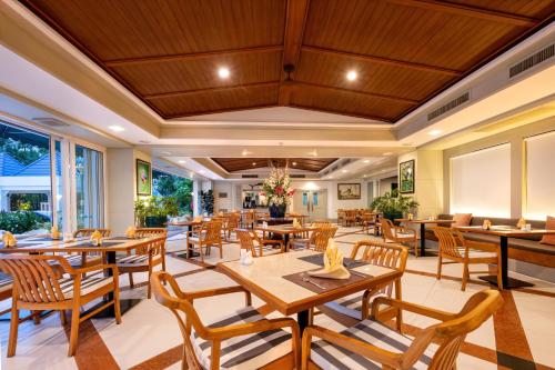 a restaurant with wooden tables and wooden chairs at Andaman Beach Suites Hotel, Patong Phuket in Patong Beach