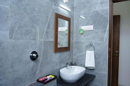 ein Badezimmer mit einem weißen Waschbecken und einem Spiegel in der Unterkunft HOTEl MARKS INN in Munirābād