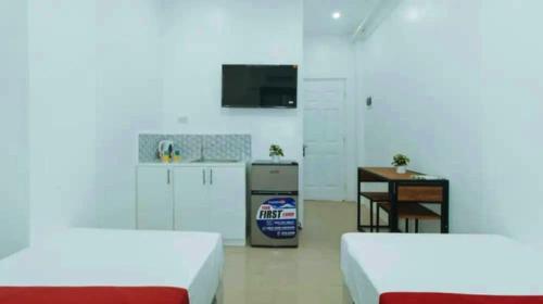two beds in a room with a kitchen and a table at Greenwood Residences in Bacolod
