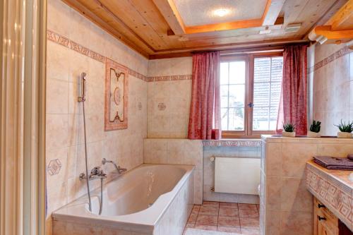 a bathroom with a tub and a window at Hotel Bären Amriswil in Amriswil