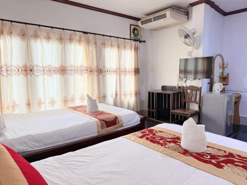 a hotel room with two beds and a refrigerator at Vangvieng Sisavang Mountain View Hotel in Vang Vieng
