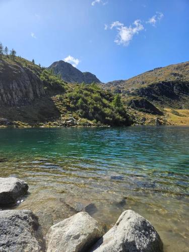 a body of water with rocks in front of a mountain at Residence Sole Alto Marillleva 1400 - vista bosco in Marilleva