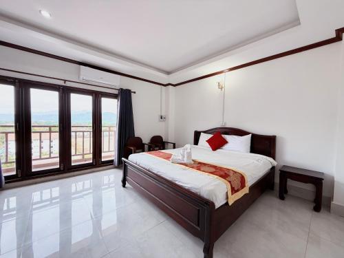 a bedroom with a bed and a large window at Vangvieng Sisavang Mountain View Hotel in Vang Vieng