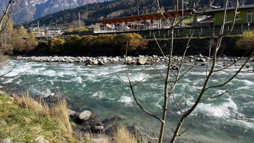 a river with a bridge over it with rocks at Residence Sole Alto Marillleva 1400 - vista bosco in Marilleva