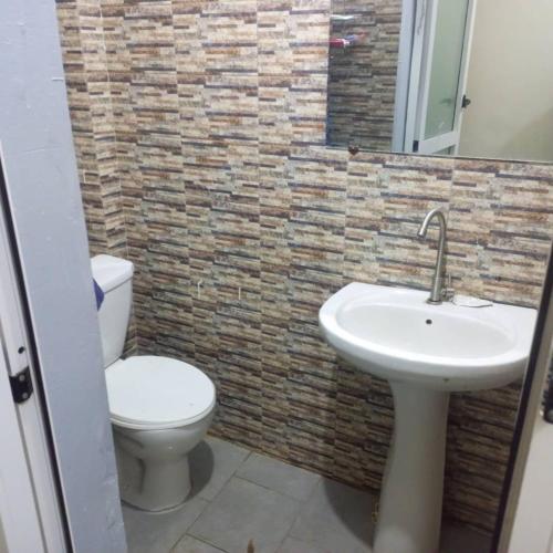 Un baño con un lavabo blanco y un inodoro. en Appartement chez Alioune, en Tilel