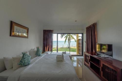 a bedroom with a large bed with a view of the ocean at Villa Phra Chan Resort in Ban Pak Nam Khem Nu