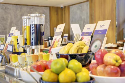 a table with bowls of apples and bananas and juice at Cygnett Inn Airport in Mohāna