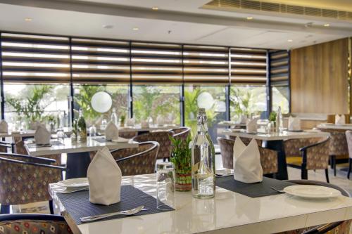 a restaurant with tables and chairs and a large window at Cygnett Inn Airport in Mohāna