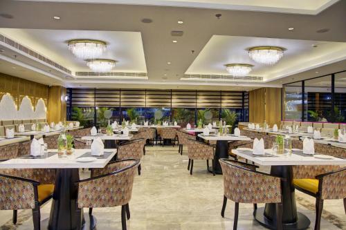 a restaurant with tables and chairs and windows at Cygnett Inn Airport in Mohāna