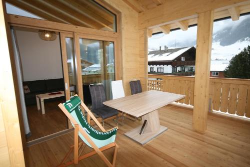 a wooden porch with a wooden table and chairs at Großglockner Goldried Chalet in Kals am Großglockner