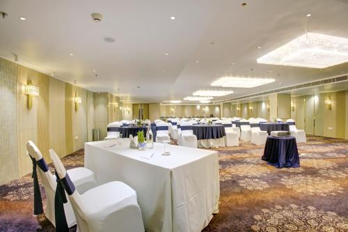 a large room with tables and white chairs and tablesearcher at Cygnett Inn Airport in Mohāna