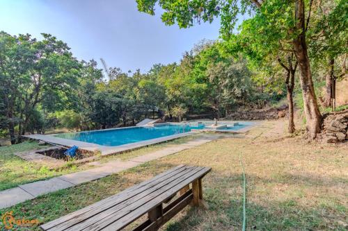 a swimming pool in a park with a bench at Avanti Kalagram Hill Top Resort, Mulshi in Kolvan