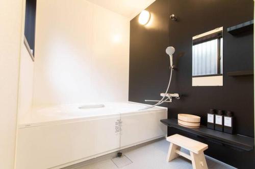 a bathroom with a white tub and a stool at Goemon House 五右衛門ハウス in Osaka