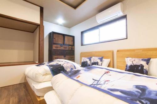 a bedroom with two beds and a window at Goemon House 五右衛門ハウス in Osaka