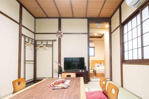 a dining room with a table and chairs and a television at Goemon House 五右衛門ハウス in Osaka